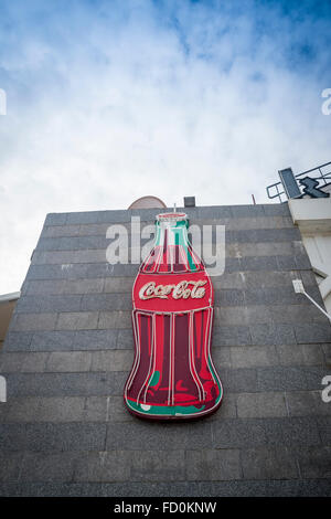 Große Leuchtreklame Coca Cola Flasche Zeichen an der Seite eines Gebäudes. Stockfoto