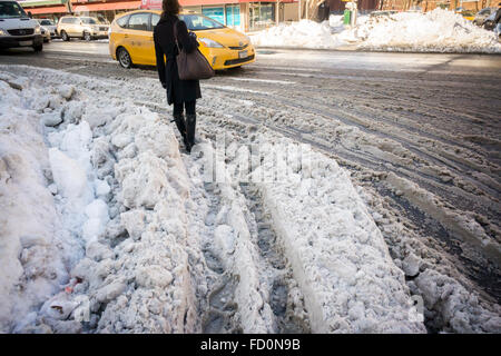 Fußgänger-Ochsentour durch Pfützen, Matsch und Schnee während ihren morgendlichen pendeln Montag, 25. Januar 2016 an Straßenkreuzungen mit Schnee dam verstopfte Abflüsse im New Yorker Stadtteil Chelsea. Winter Sturm Jonas gedumpten 26,8 Zoll auf Central Park machen es den zweithöchsten Betrag, da Aufzeichnungen begann im Jahre 1869 und mit Temperaturen über dem Gefrierpunkt einige, dass der Schnee schmilzt. (© Richard B. Levine) Stockfoto