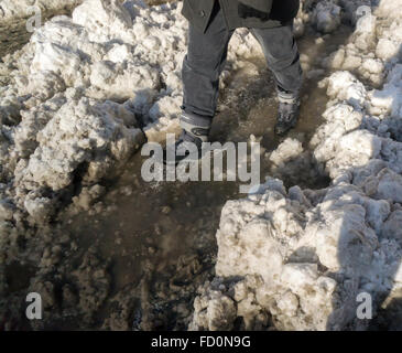 Fußgänger-Ochsentour durch Pfützen, Matsch und Schnee während ihren morgendlichen pendeln Montag, 25. Januar 2016 an Straßenkreuzungen mit Schnee dam verstopfte Abflüsse im New Yorker Stadtteil Chelsea. Winter Sturm Jonas gedumpten 26,8 Zoll auf Central Park machen es den zweithöchsten Betrag, da Aufzeichnungen begann im Jahre 1869 und mit Temperaturen über dem Gefrierpunkt einige, dass der Schnee schmilzt. (© Richard B. Levine) Stockfoto