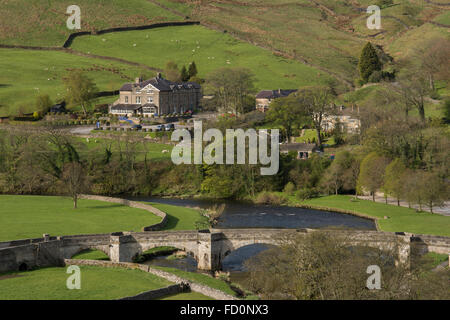 Yorkshire Dales Blick auf Brücke über Fluß Wharfe & Devonshire fiel Hotel auf sanften grün, Hügeln jenseits - Burnsall, England, GB, UK. Stockfoto