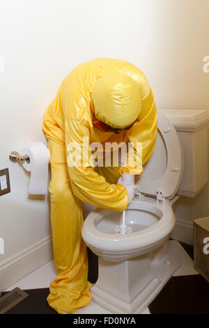 Frau, gekleidet in gelben Haz-Mat-Uniform und Ventilator Bad WC mit Bürste reinigen. Stockfoto