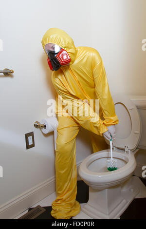 Frau, gekleidet in gelben Haz-Mat-Uniform und Ventilator Bad WC mit Bürste reinigen. Stockfoto