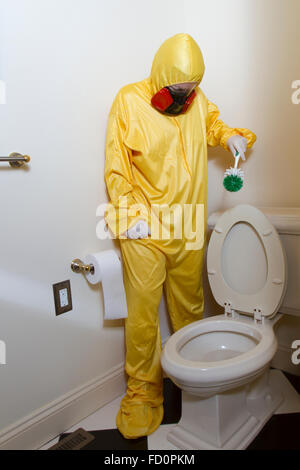 Frau, gekleidet in gelben Haz-Mat-Uniform und Ventilator Bad WC mit Bürste reinigen. Stockfoto