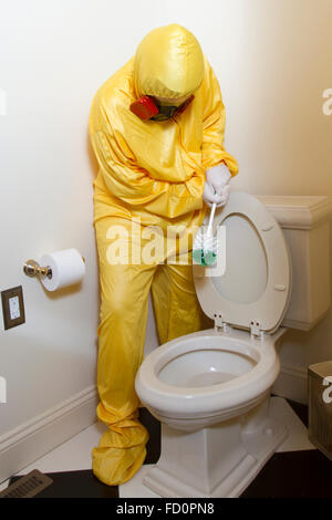 Frau, gekleidet in gelben Haz-Mat-Uniform und Ventilator Bad WC mit Bürste reinigen. Stockfoto