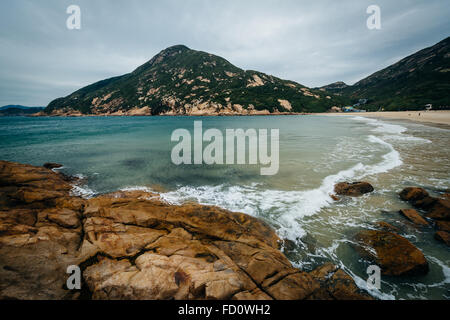 Felsenküste und Blick auf D'Aguilar Peak, Shek O Beach auf Hong Kong Island, Hongkong. Stockfoto