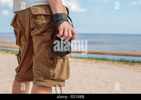 Mandressed in Hemd und Hosen, stehend auf dem sandigen Ufer des Meeres und Kamera halten. Stockfoto