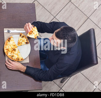 Obere Ansicht einer junger Mann essen Pizza in einem Restaurant. Stockfoto