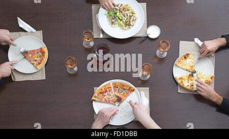 Draufsicht der Freunde Essen Pizza und Salat auf einem hölzernen Tisch in einem Restaurant. Stockfoto