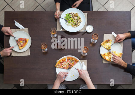 Draufsicht der Freunde Essen Pizza und Salat auf einem hölzernen Tisch in einem Restaurant. Stockfoto