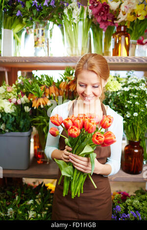 Glückliche Frau mit Haufen von frischen roten Tulpen arbeitet in ihrem shop Stockfoto