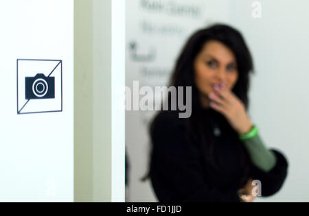 Düsseldorf, Deutschland. 17. Januar 2016. Eine junge Frau steht neben einem Piktogramm kennzeichnet "Keine fotografieren", befestigt an einer Wand im Museum Kunstpalast in Düsseldorf, 17. Januar 2016. Ein Verbot für die Bilder gilt für viele Museen in Deutschland, die zeitgenössischen Kunst aufgrund urheberrechtlicher Beschränkungen aufweisen. Foto: Monika Skolimowska/Dpa/Alamy Live News Stockfoto