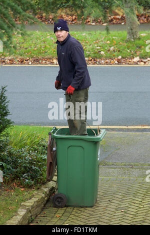 Mann, die Komprimierung von Gartenabfällen in einem grünen Wheelie-Lagerplatz Stockfoto