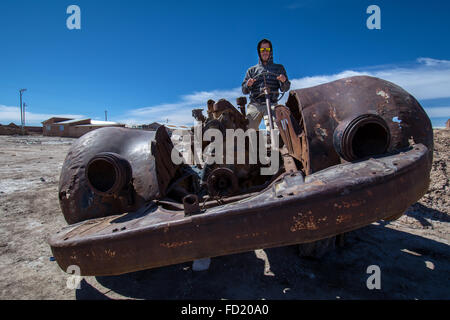 Junger Mann im rostigen alten Auto, Cementerio de los Trenes, Gemeinde Uyuni, Departamento Potosí, Altiplano, Bolivien Stockfoto