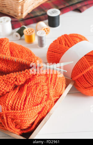 Knitting needles and balls of orange wool a knitting or needlework concept Stockfoto