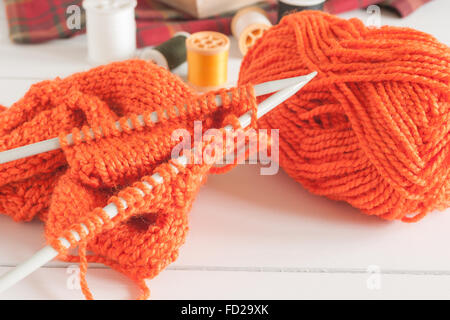 Stricken Strickjacke mit Nadeln und Kugeln von Orange wolle eine Stricknadel oder Handarbeit Konzept Stockfoto