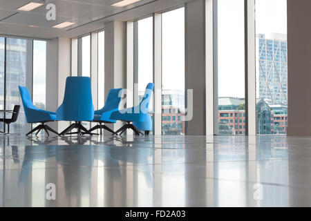 Moderne Büroeinrichtung mit Glasfenster und bequeme blaue Sessel in der Ecke Stockfoto
