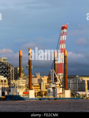 Die Offshore-Jack-up-Rig, Arbeitsbühne & Kranschiff Vidar, vertäut am Kreuzfahrtterminal, Hafen von Liverpool für Reparaturen. Im Besitz der in Luxemburg ansässigen Jan de Nul Group, die Dienstleistungen für maritime Infrastruktur bietet. Es hilft bei Bau und Wartung das Schiff ist 140,4m in der Länge. Der Schwerlastkran kann bis zu 1200 Tonnen heben und ist im Hafen, um mit Geräten speziell für die Installation von Offshore-Windparks ausgestattet werden. Die Skyline von Liverpool und die drei Wahrzeichen von Liverpool. Stockfoto