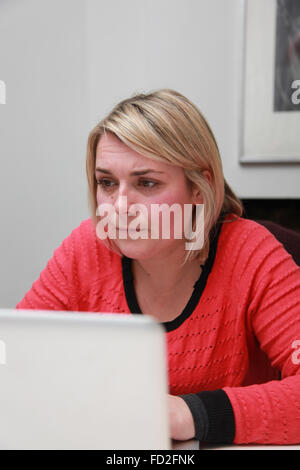 Müde, junge Frau auf ihrem Laptop arbeiten Stockfoto
