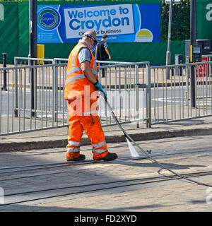 Man Druck waschen Straßenbahnpunkte in Croydon Tramlink Gleise in der Straße mit "Welcome to Croydon" Plakat jenseits London England UK Stockfoto