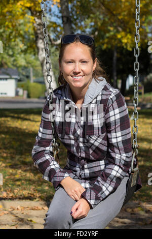 Lächelnde Frauen auf einer Schaukel im Herbst Stockfoto