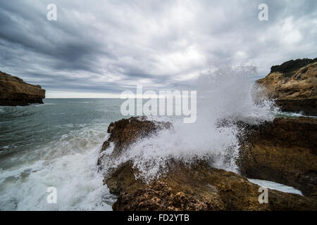 Wellen, die auf Felsen am Praia de Albandeira in der Algarve in Portugal. Stockfoto