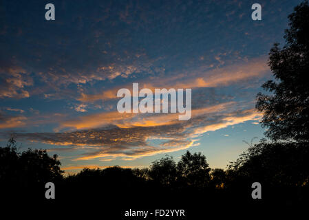 Einen schönen September-Sonnenuntergang mit hohen Wolkenfetzen das letzte Sonnenlicht fangen. Stockfoto