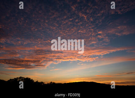 Einen schönen September-Sonnenuntergang mit hohen Wolkenfetzen das letzte Sonnenlicht fangen. Stockfoto