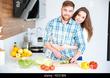 Glückliches junges Paar Kochen und umarmt auf dem Küchentisch Stockfoto