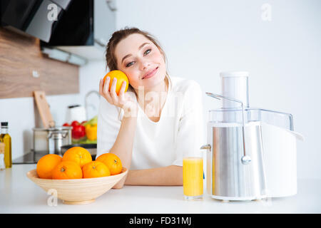 Porträt von niedlichen schönen jungen Frau macht Orangensaft auf die Küche Stockfoto