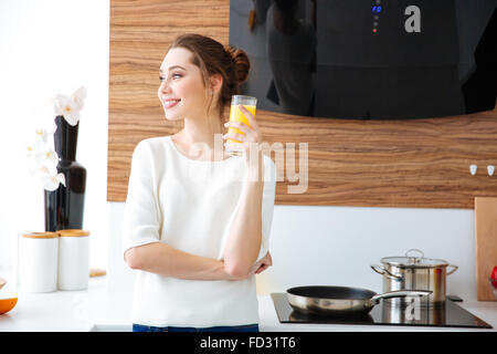 Porträt von schöne fröhliche junge Frau auf dem Küchentisch Saft zu trinken Stockfoto