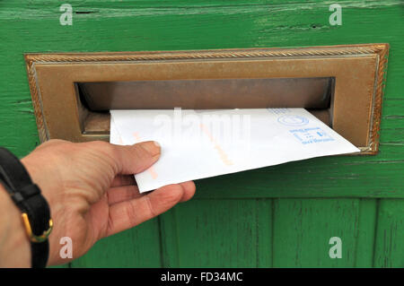 Lieferung eines Briefes durch einen Briefkasten einer Holztür Front Briefträger. Stockfoto