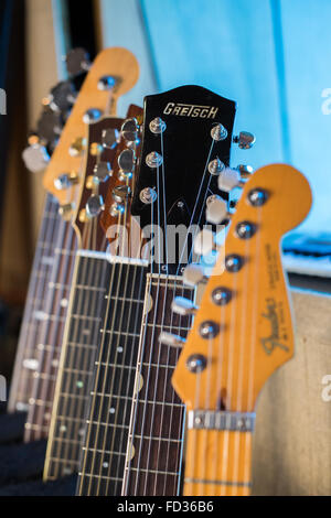 E-Gitarren, akustische Gitarren und elektrischen Bassgitarren auf einem Gestell in einem Studio zeigt der Hals, Griffbrett und Saiten Stockfoto