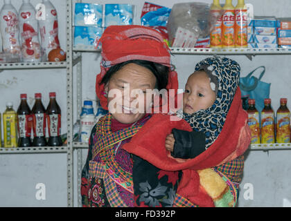 Ladenbesitzer mit Kind auf ihrem Rücken, Datang Dorf, Guizhou Provinz, China Stockfoto