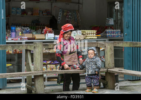 Ladenbesitzer mit neugieriger kleiner Junge, Datang Dorf, Guizhou Provinz, China Stockfoto