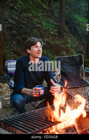 Ein junger Mann sitzt am Lagerfeuer Geschichten zu erzählen, mit Freunden in Big Sur, Kalifornien. Stockfoto