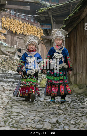 Zwei Mädchen lange Rock Miao hinunter eine Dorfstraße, Langde Shang Miao Dorf, Guizhou Provinz, China Stockfoto