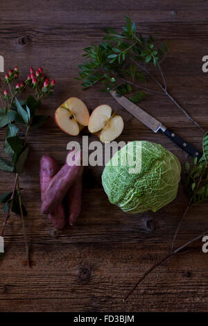 Wirsing, Apfel und Süßkartoffeln als Zutaten für einen gesunden Salat auf einem rustikalen Holztisch Stockfoto