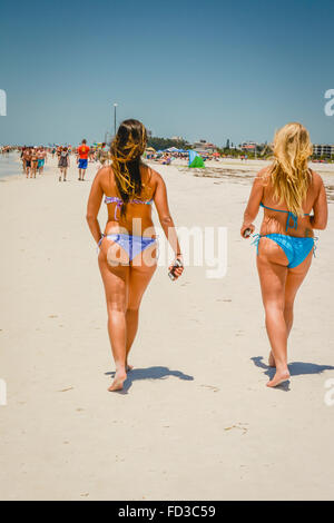 Ansicht von hinten von zwei langhaarige Blonde und Brünette Frauen einem Spaziergang Strand mit knappen blauen Bikini Bottoms auszusetzen genügend Popos Stockfoto