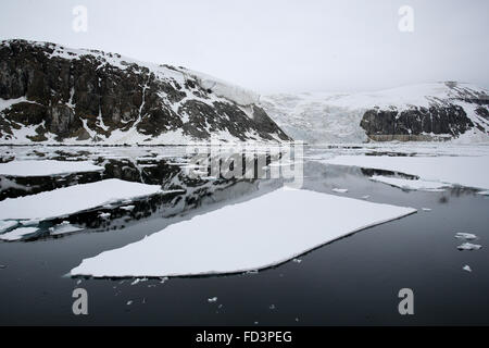 Svalbard, Spitzbergen, Alkefjellet. Gletscher, schneebedeckte Klippen und Meereis. Stockfoto