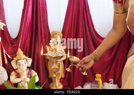 Die Hand der Frau zu beleuchten, die Metall Diya. Traditionelle indische Hindus religiöse Zeremonie. Konzentrieren Sie sich auf die Öllampe. Indien besonderes ritual Stockfoto