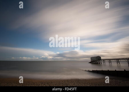 Langzeitansicht über Selsey Lifeboat Station und Pier in Sussex, Großbritannien, mit Meer und sich bewegenden Wolken. Moody Abstract. Stockfoto