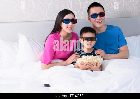 Familie vor dem 3D Fernseher im Bett mit popcorn Stockfoto