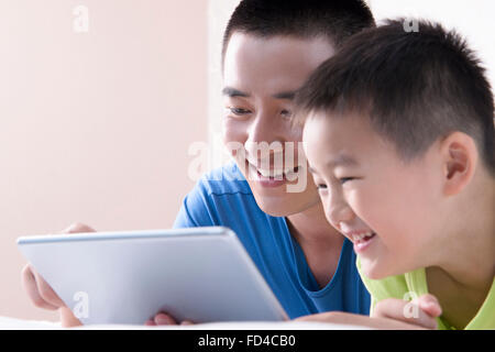 Vater und Sohn mit digital-Tablette im Bett Stockfoto