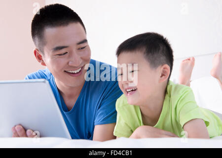 Vater und Sohn mit digital-Tablette im Bett Stockfoto