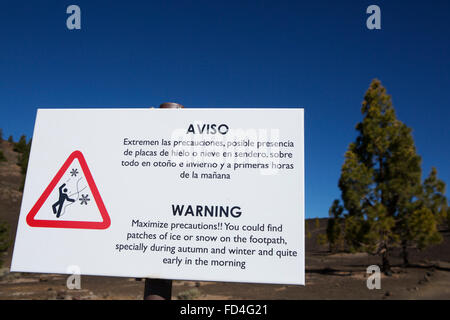 Ein Warnsignal für Eis auf Wanderwegen im Nationalpark Teide auf Teneriffa, Spanien. Kanarische Kiefern säumen die kargen Landschaft. Stockfoto