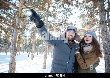 Glückliches Paar in warme Kleidung zeigt und das Nachschlagen in Winter park Stockfoto