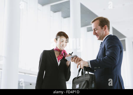 Japanische attraktive Stewardess helfen Kunden am Flughafen Stockfoto