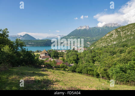 Blick über Dorf und Burg von Duingt am Lac d ' Annecy mit Felswänden und grünen Wäldern des Gebirges Savoie, Frankreich Stockfoto