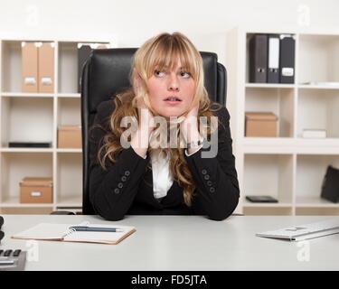 Junge Geschäftsfrau sitzen Denken mit dem Kopf in die Hände, als sie bei ihrem Deskstaring in die Luft sitzt. Stockfoto