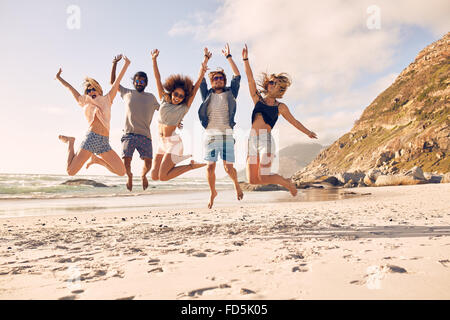 Gruppe von Freunden zusammen am Strand Spaß haben. Glückliche junge Menschen springen am Strand. Gruppe von Freunden genießen Sommer vac Stockfoto